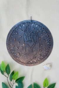 Round gautam buddha lippan art displaying a hand in a mudra gesture, patterns and raised dots, evoking a spiritual and calming tone.