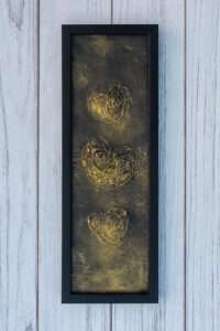 Three textured golden hearts are vertically aligned in a heart painting. The swirling patterns convey a sense of warmth and elegance.