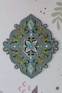 Ornate gray wall decoration with a central floral motif, surrounded by intricate yellow and blue designs. Elegant, symmetrical, and decorative.