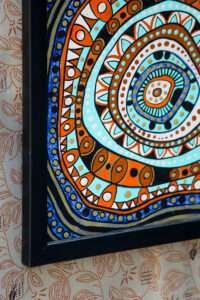 Framed abstract painting with concentric circles and geometric patterns in vibrant blues, oranges, and browns. Energetic and dynamic design.