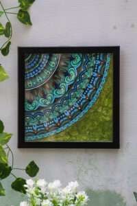 Framed mandala painting featuring intricate, blue-green mandala patterns on the upper left, blending into textured green brushstrokes on the bottom right.