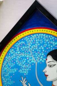 Framed vibrant artwork featuring a woman's profile with ornate black hair, set against a swirling blue tree pattern. The mood is serene and contemplative.