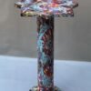 Shop coffee table that has Colorful patterns in blue, red, and yellow hues. It stands on a cylindrical base, conveying an artistic and whimsical tone.
